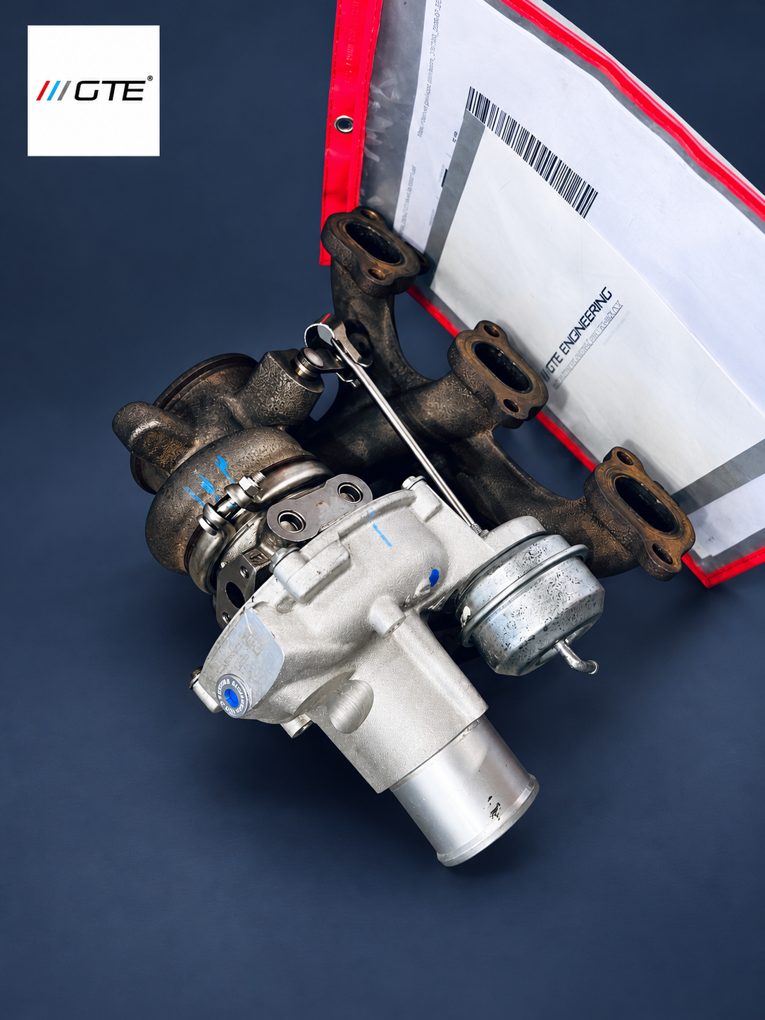 Maserati turbocharger rebuilt by GTE Engineering, shown with wastegate actuator, exhaust manifold and service paperwork; workshop service example.