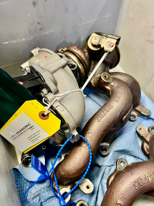 Workshop example of a Maserati V6 turbocharger with protective covers, manifold and inspection tag
