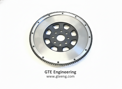 Original flywheel service-example image showing a silver friction face, black center and toothed ring gear; exact application varies.