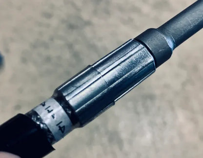 Original shared hydraulic-hose workmanship example showing a metal crimp sleeve, black hose and identification band; not a model-specific hose