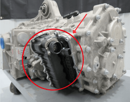 Original McLaren transmission photograph with the shift actuator circled and indicated by a red arrow; surrounding gearbox is location context.